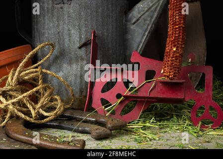 Verrostete und abgenutzte landwirtschaftliche Gegenstände auf dem mit Heu bedeckten Holzboden. Stockfoto