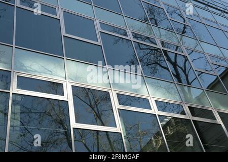 Außenfenster EINES modernen Bürogebäudes. Niedrige Ansicht einer modernen Glasfassade mit Reflexen Stockfoto