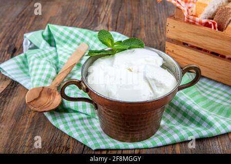 Wasser Büffeljoghurt fermentiert in Kupferschüssel. Hausgemachter Joghurt in Schüssel auf Holztisch, Draufsicht, Kopierplatz. Bio-reiner griechischer Joghurt für gesundes b Stockfoto