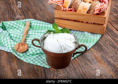 Wasser Büffeljoghurt fermentiert in Kupferschüssel. Hausgemachter Joghurt in Schüssel auf Holztisch, Draufsicht, Kopierplatz. Bio-reiner griechischer Joghurt für gesundes b Stockfoto