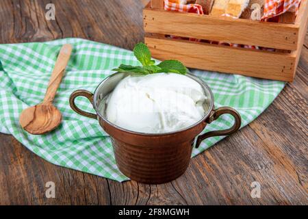 Wasser Büffeljoghurt fermentiert in Kupferschüssel. Hausgemachter Joghurt in Schüssel auf Holztisch, Draufsicht, Kopierplatz. Bio-reiner griechischer Joghurt für gesundes b Stockfoto