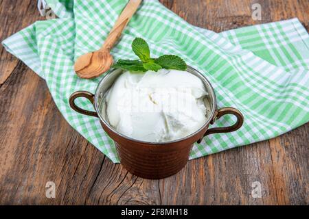 Wasser Büffeljoghurt fermentiert in Kupferschüssel. Hausgemachter Joghurt in Schüssel auf Holztisch, Draufsicht, Kopierplatz. Bio-reiner griechischer Joghurt für gesundes b Stockfoto