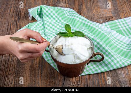 Wasser Büffeljoghurt fermentiert in Kupferschüssel. Hausgemachter Joghurt in Schüssel auf Holztisch, Draufsicht, Kopierplatz. Bio-reiner griechischer Joghurt für gesundes b Stockfoto