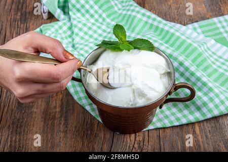 Wasser Büffeljoghurt fermentiert in Kupferschüssel. Hausgemachter Joghurt in Schüssel auf Holztisch, Draufsicht, Kopierplatz. Bio-reiner griechischer Joghurt für gesundes b Stockfoto