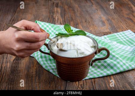 Wasser Büffeljoghurt fermentiert in Kupferschüssel. Hausgemachter Joghurt in Schüssel auf Holztisch, Draufsicht, Kopierplatz. Bio-reiner griechischer Joghurt für gesundes b Stockfoto