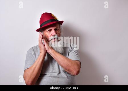 Alter amerikanischer Rüde mit grauem Hemd und roter Fedora hat zeigt an, dass er müde ist Stockfoto