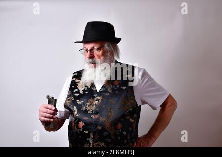 Altes Männchen in einer schicken Seidenweste mit einem Kolben Mit Alkohol Stockfoto