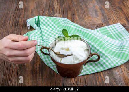 Wasser Büffeljoghurt fermentiert in Kupferschüssel. Hausgemachter Joghurt in Schüssel auf Holztisch, Draufsicht, Kopierplatz. Bio-reiner griechischer Joghurt für gesundes b Stockfoto