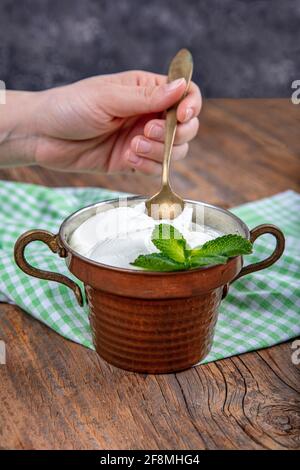 Wasser Büffeljoghurt fermentiert in Kupferschüssel. Hausgemachter Joghurt in Schüssel auf Holztisch, Draufsicht, Kopierplatz. Bio-reiner griechischer Joghurt für gesundes b Stockfoto