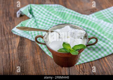 Wasser Büffeljoghurt fermentiert in Kupferschüssel. Hausgemachter Joghurt in Schüssel auf Holztisch, Draufsicht, Kopierplatz. Bio-reiner griechischer Joghurt für gesundes b Stockfoto