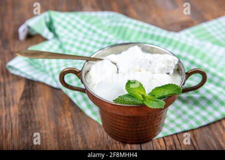 Wasser Büffeljoghurt fermentiert in Kupferschüssel. Hausgemachter Joghurt in Schüssel auf Holztisch, Draufsicht, Kopierplatz. Bio-reiner griechischer Joghurt für gesundes b Stockfoto