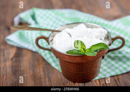 Wasser Büffeljoghurt fermentiert in Kupferschüssel. Hausgemachter Joghurt in Schüssel auf Holztisch, Draufsicht, Kopierplatz. Bio-reiner griechischer Joghurt für gesundes b Stockfoto