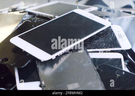 Defektes Handy und Pad mit abgestürzten Bildschirm Glas LCD. Gadgets liegen auf einem anderen. Geräte sind für die Nutzung vorbereitet. Stockfoto