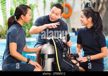 Asiaten in der Diver Kurs in der Tauchschule im Neoprenanzug mit einer Sauerstoffflasche Stockfoto