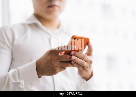 Asiatischer Geschäftsmann mit Smartphone am Fenster Stockfoto