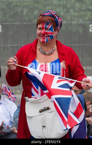 Eine Frau im Kleid von Union Jack, die Teil einer großen Menschenmenge ist, die sich auf dem Trafalgar Square versammelt hat, um einen riesigen Fernseher zu sehen, der ihre Königliche Hoheit, Königin Elizabeth ii., die Feierlichkeiten zum Diamantenjubiläum zeigt. Trafalgar Square, London, Großbritannien. 5 Juni 2012 Stockfoto