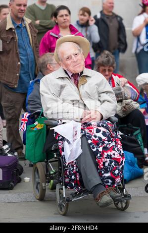 Ein Mann in einem Rollstuhl, der eine Prinz-Philip-Maske trägt, Teil einer großen Menschenmenge, traf sich auf dem Trafalgar Square, um einen riesigen Fernseher zu sehen, der ihre Königliche Hoheit, Königin Elizabeth ii, zum Diamantenjubiläum zeigt. Trafalgar Square, London, Großbritannien. 5 Juni 2012 Stockfoto