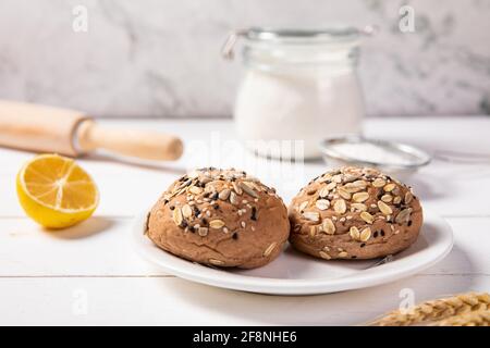 Nahaufnahme von frisch gebackenem Mehrkorngetreide gesund Brotbrötchen auf einem weißen Teller Stockfoto