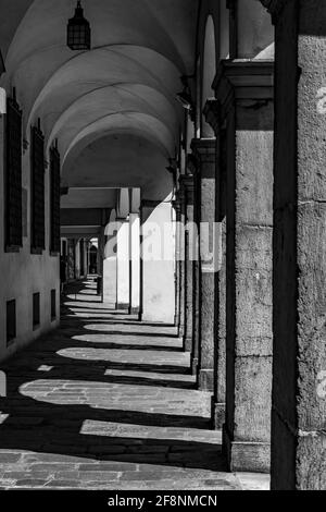 Graustufenaufnahme des Korridors eines schönen Gebäudes mit Säulen und Bögen Stockfoto