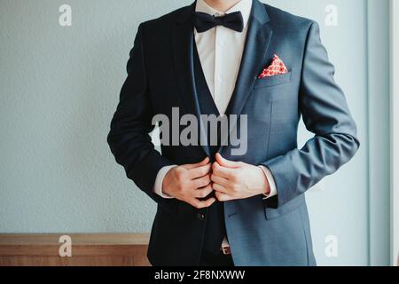 Mann in einem schönen Anzug mit Fliege knöpfend seine gekleidet Jacke Stockfoto