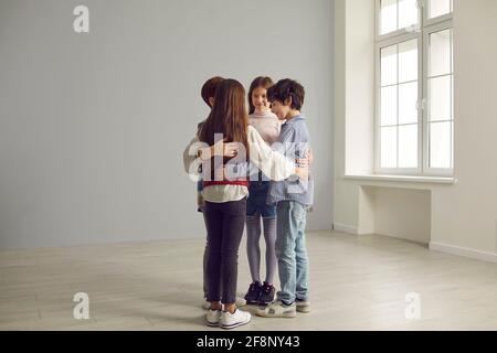 Eine kleine Gruppe von Schulkindern, die sich im Kreis befinden Geräumiges, leeres Zimmer Stockfoto