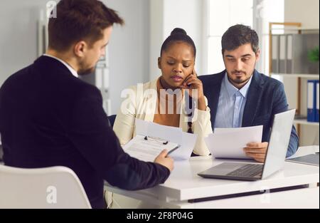 Das verheiratete Paar prüft sorgfältig einen wichtigen Vertrag, während es in einer Sitzung in einem Bankbüro sitzt. Stockfoto