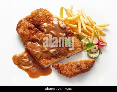 Draufsicht auf köstliches, gebratenes paniertes Fleisch, das mit klassischem Fleisch bedeckt ist chasseur-Sauce serviert mit Pommes Frites und Salat Stockfoto