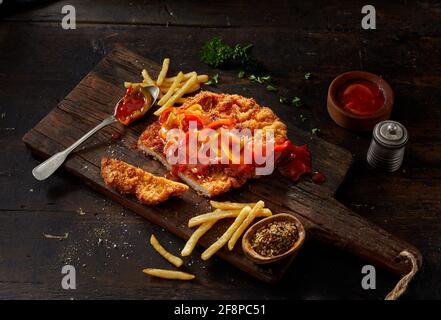 Hoher Winkel von leckeren frittierten panierten Schweineschnitzel mit traditionellen Deutsche Zigeunersauce mit Paprika und Paprika serviert Pommes frites auf rustikalem Stockfoto