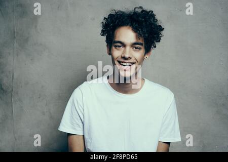 Ein Typ mit lockigen Haaren in einem weißen T-Shirt sitzt darauf Stühle Studio Stockfoto