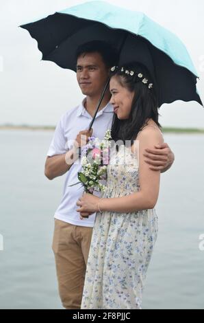 Ein indonesisches Paar mit einem Regenschirm und Blumen. Stockfoto