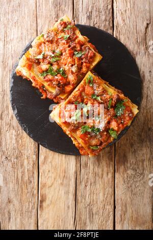 Lasagne Vincisgrassi Rezept mit Hähnchengiblets, Rind, Schwein und Gemüse aus nächster Nähe auf einem Schieferbrett auf dem Tisch. Vertikale Draufsicht von oben Stockfoto