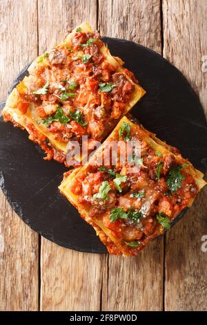 Der italienische Vincisgrassi oder vincesgrassi ist ein typisches Pasta-Gericht der Marken, ähnlich wie Lasagne al forno closeup in der Schiefertafel auf dem Tisch. Vertikal oben Stockfoto