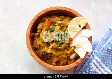 Baigan Bharta, auch Vangyache Bharit in Marathi genannt. Es handelt sich um ein geröstetes Auberginen-getrocknetes. Brinjaler Chutney. Serviert in einer Holzschale mit Roti. Stockfoto