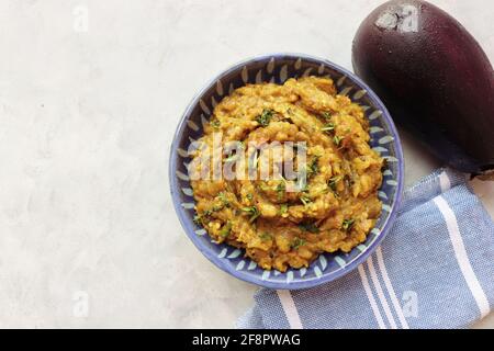 Baigan Bharta, auch Vangyache Bharit in Marathi genannt. Es handelt sich um ein geröstetes Auberginen-getrocknetes. Brinjaler Chutney. Serviert in einer Holzschale mit Roti. Stockfoto