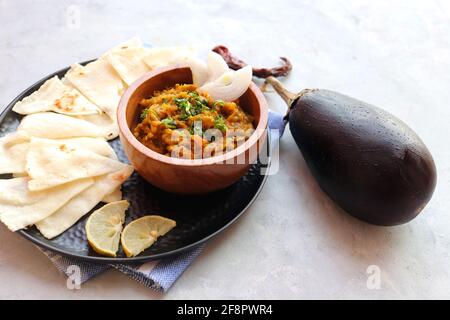 Baigan Bharta, auch Vangyache Bharit in Marathi genannt. Es handelt sich um ein geröstetes Auberginen-getrocknetes. Brinjaler Chutney. Serviert in einer Holzschale mit Roti. Stockfoto