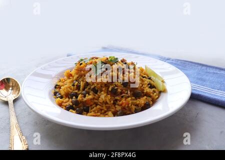 Indische Küche - Kichererbsen Biryani, chole Pulao. Garniert mit gebratener Zwiebel, gehacktem Koriander und Zitronenkeilen. Kala chana biryani. Raum kopieren Stockfoto