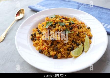 Indische Küche - Kichererbsen Biryani, chole Pulao. Garniert mit gebratener Zwiebel, gehacktem Koriander und Zitronenkeilen. Kala chana biryani. Raum kopieren Stockfoto