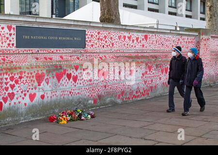 Ein maskiertes Paar blickt am 9. April 2020 auf die Covid-19-Gedenkmauer entlang der Themse in der Nähe des St. Thomas’s Hospital, während die Unterstützung wächst Stockfoto