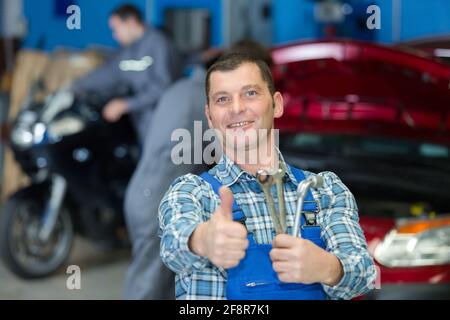 Arbeiter mit Daumen nach oben in der Garage Stockfoto