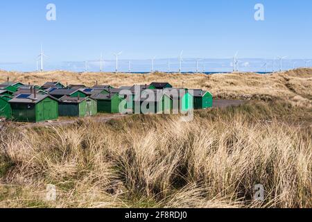 Die fishermens Hütten am South Gare, Redcar, England, Großbritannien mit Offshore- Windenergieanlagen im Hintergrund Stockfoto