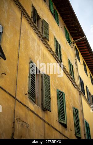 Grüne Fensterläden am Yellow Ocher-Gebäude in Florenz, Italien Stockfoto
