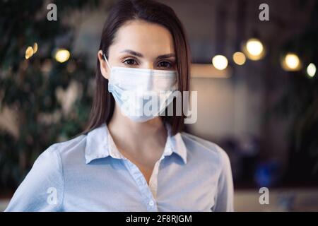 Potrait einer jungen schönen Geschäftsfrau, die eine medizinische Gesichtsmaske trägt Stockfoto