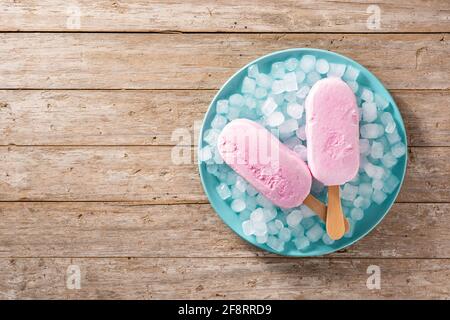 Erdbeerpopsicles und zerkleinertes Eis auf blauem Teller und Holz Tabelle Stockfoto