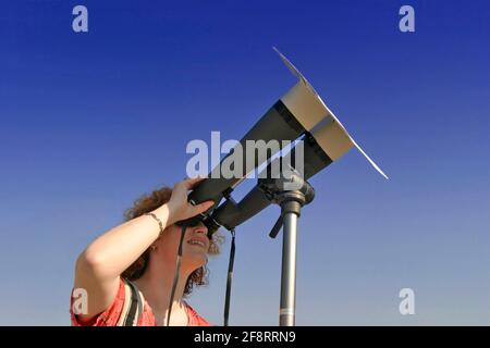 Frau, die die Sonne mit einem speziellen Fernglas beobachtet, Österreich Stockfoto