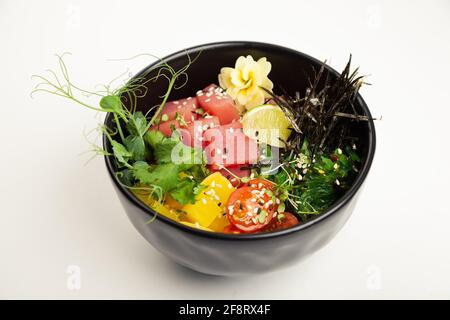 Salat mit Thunfisch in eine Schüssel geben. Zutaten frischer Thunfisch, Kirschtomaten, marinierte Algen, Reis, Takuan, Ponzu-Sauce, Teriyaki-Sauce, Nori, Sesam Stockfoto