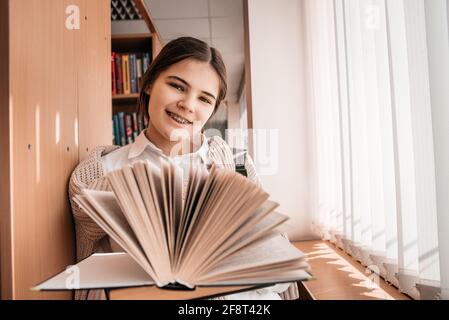 Bildung, High School, Universität, Lernkonzept - lächelndes Student Mädchen Buch in der Bibliothek zu lesen Stockfoto