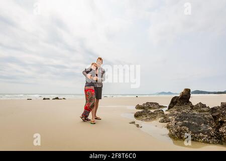 Glückliches Touristenpaar am Strand von Son Hao, Insel Quan Lan, Bai TU Long Bay, Vietnam. Landschaftsfoto am Meer, aufgenommen in Südostasien, Ha Long-Gebiet. Stockfoto