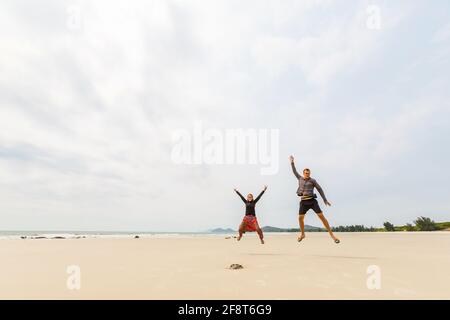 Glückliches Touristenpaar am Strand von Son Hao, Insel Quan Lan, Bai TU Long Bay, Vietnam. Landschaftsfoto am Meer, aufgenommen in Südostasien, Ha Long-Gebiet. Stockfoto