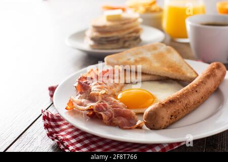 Traditionelles amerikanisches Frühstück mit Spiegelei, Toast, Speck und Wurst auf Holz Tabelle Stockfoto