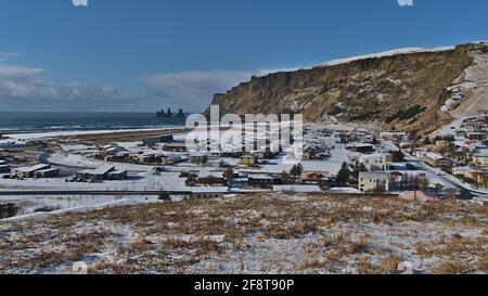 Schöne Aussicht über das kleine Dorf Vik an der Südküste Islands in der Wintersaison mit schneebedeckter Landschaft und Felsformationen. Stockfoto